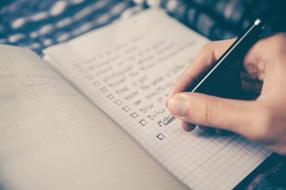 Notizbuch mit handschriftlicher Liste, daneben ein Stift