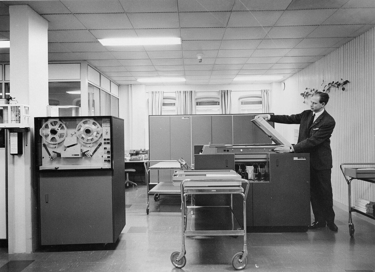 Mann legt Papier in eine Maschine in einem Rechenzentrum der 1960er Jahre